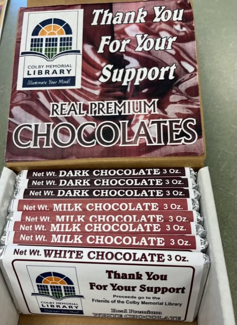 A box of Colby Memorial Library fundraising chocolate bars in three flavors: dark chocolate, milk chocolate, and white chocolate. The box says, “Thank You For Your Support” and “REAL PREMIUM CHOCOLATES.”.
